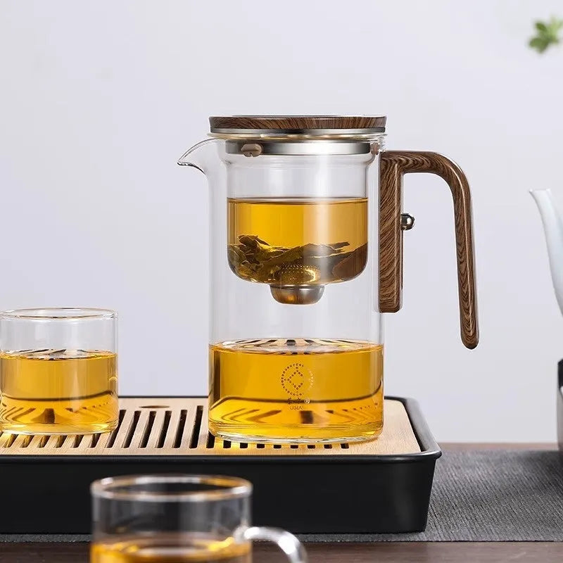 Glass teapot with wooden handle showing magnetic tea separation button and drip-free spout.