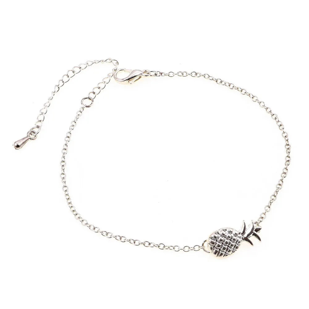 Gold and silver alloy pineapple charm bracelet on wrist, showing adjustable clasp.