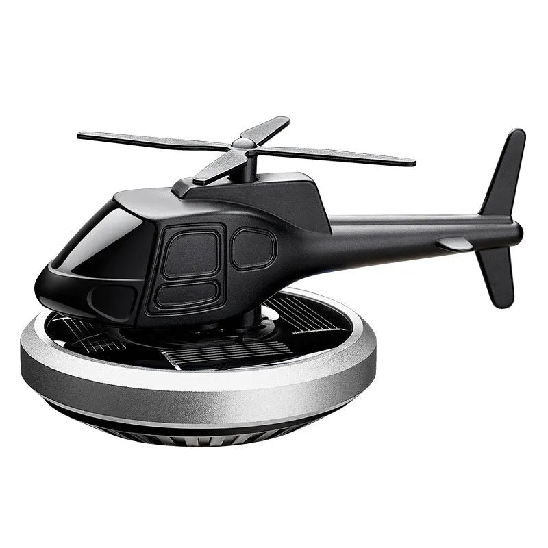 Silver metallic solar-powered helicopter car perfume ornament rotating on a car dashboard