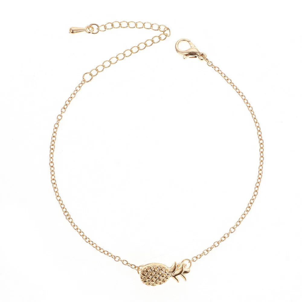 Gold and silver alloy pineapple charm bracelet on wrist, showing adjustable clasp.