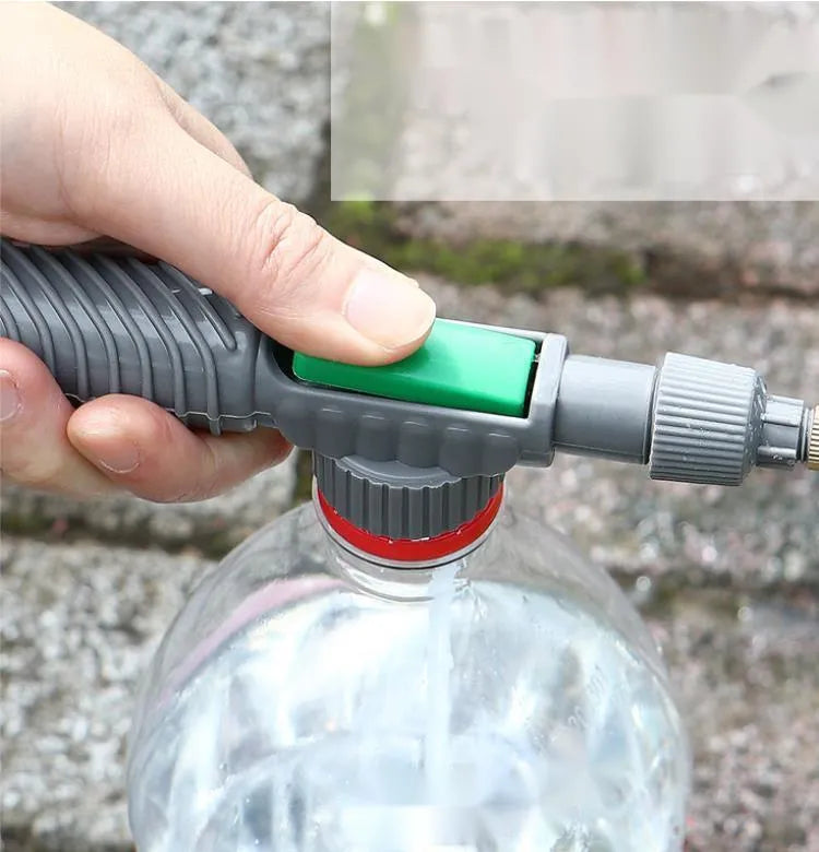 Plastic watering sprayer nozzle with extension tube attached to a large clear beverage bottle.