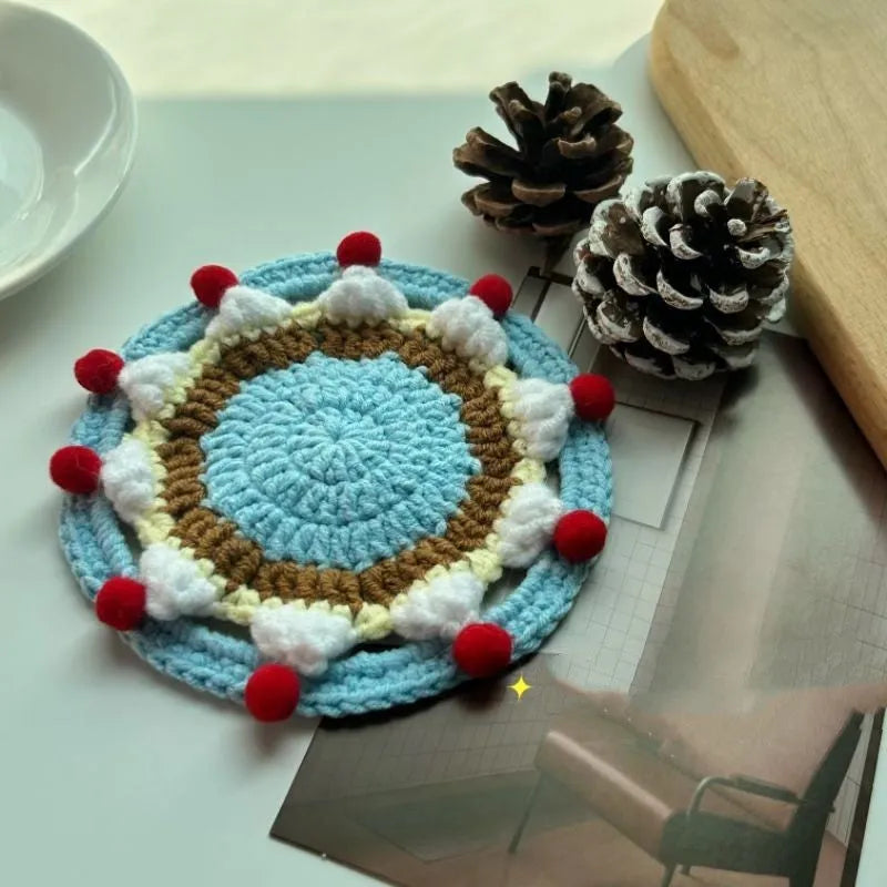 Circular wool felt coaster with cake design, 9 cm in diameter, shown on a table.