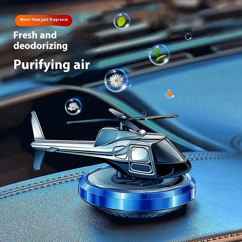Silver metallic solar-powered helicopter car perfume ornament rotating on a car dashboard