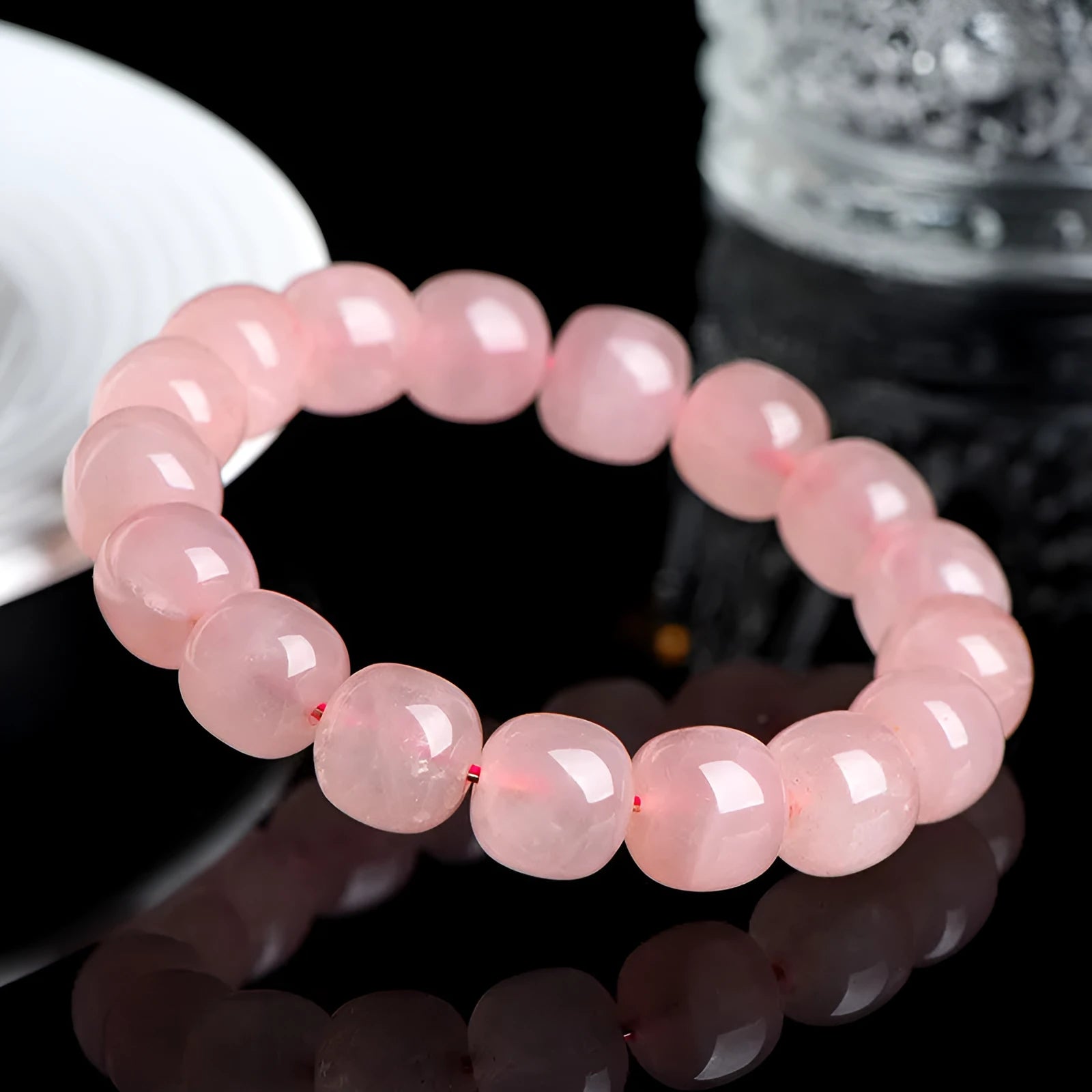 Natural pink crystal barrel bead bracelet with geometric design on a wrist.
