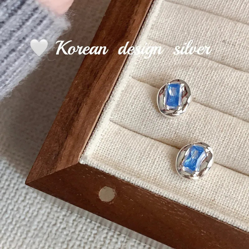 Silver geometric earrings with oval blue diamond wrapped in heart motif