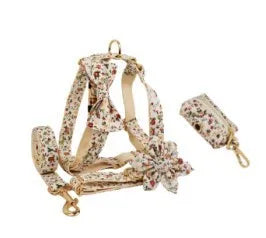 Small white flower pet dog collar set with matching vest, leash, bow, and accessories on a cloth background.