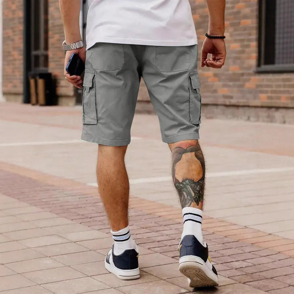 Man wearing loose grey cropped workwear shorts with a straight leg and micro-elastic fabric.