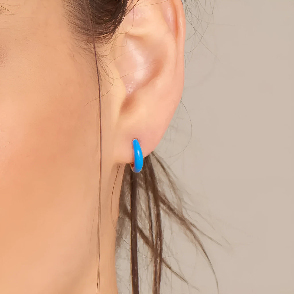 A pair of oval-shaped epoxy resin earrings on a U-shaped curved silver hook, showing a marbled colour finish.