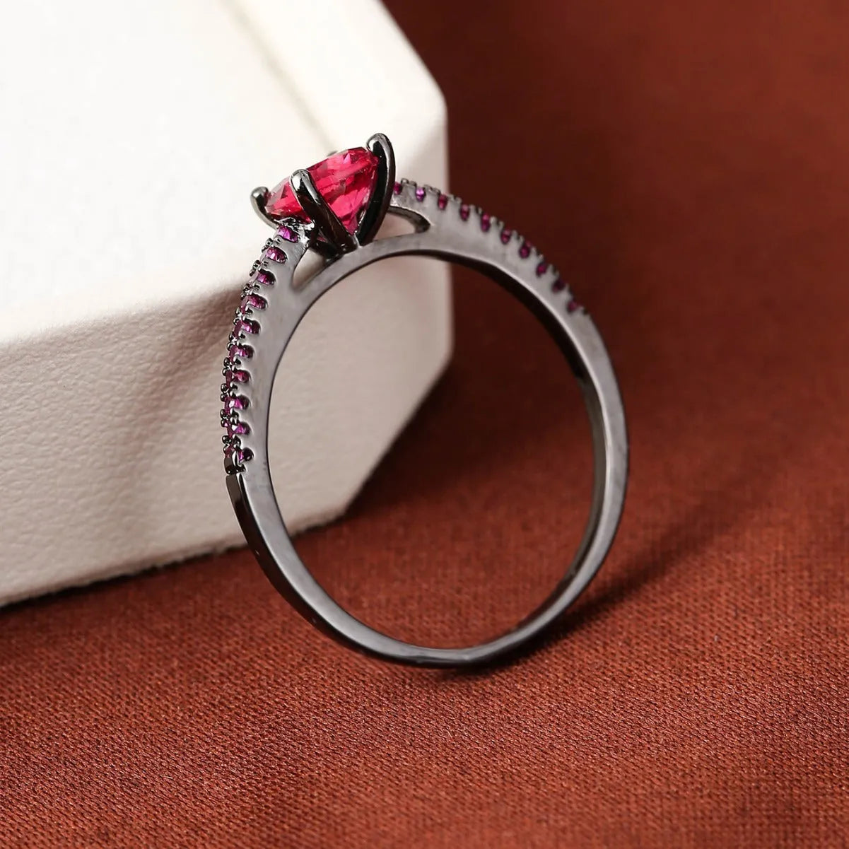 Geometric hexagon fashion ring in solid copper with an electroplated gun black purple finish, shown on a finger.