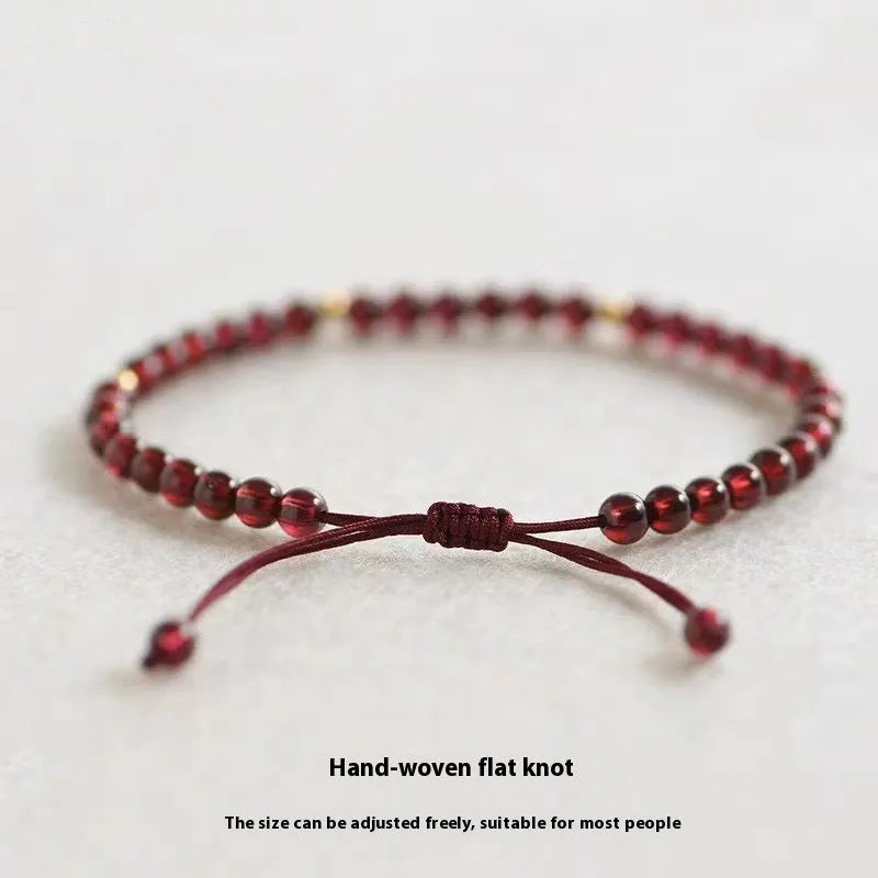 Hand-woven garnet red rope bracelet made from flexible wire, showing national tide style.