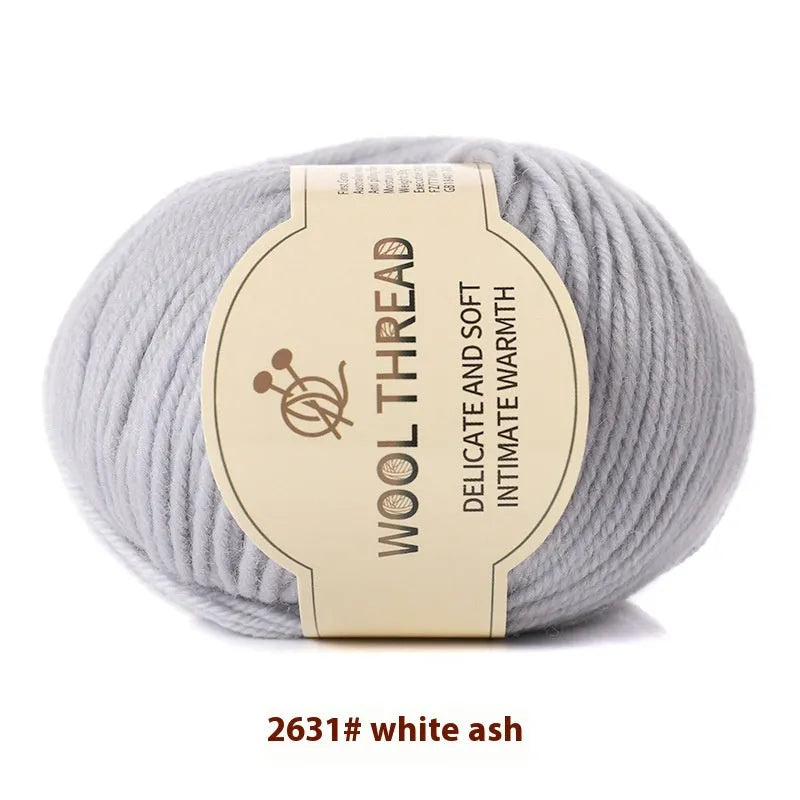 One roll of beige domestic wool hand-knitting yarn for size 10 needles next to knitting needles.
