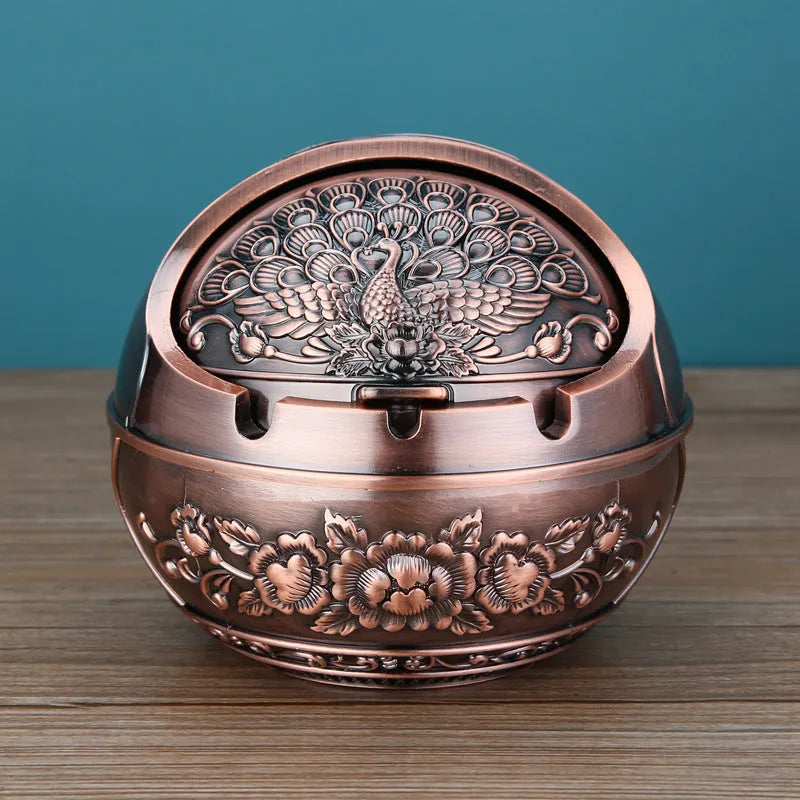 Bronze and red copper alloy decorative ashtray with smoke-extinguishing slot on a table.