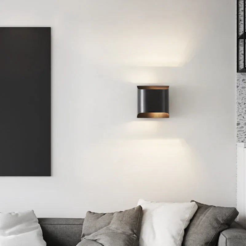 Minimalist copper wall lamp with black gold finish mounted beside bed