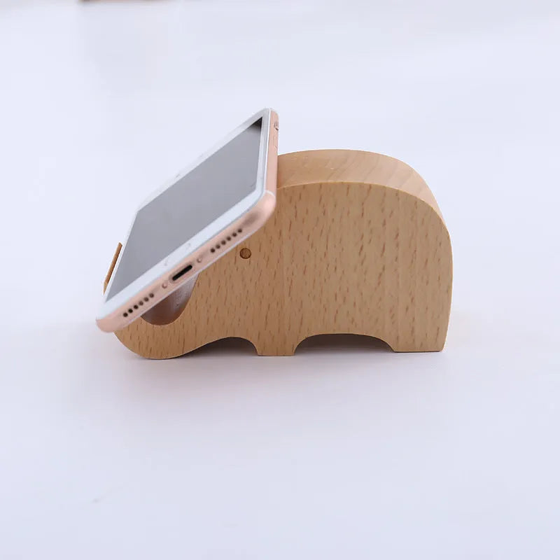 Sculpted beech wood lazy bracket phone holder with custom engraved text on a wooden desk.