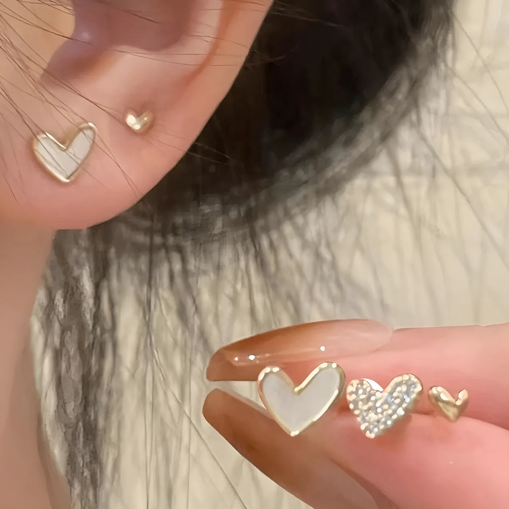 Three pairs of girly heart-shaped alloy earrings in gold, black, pink, and black and white colours.