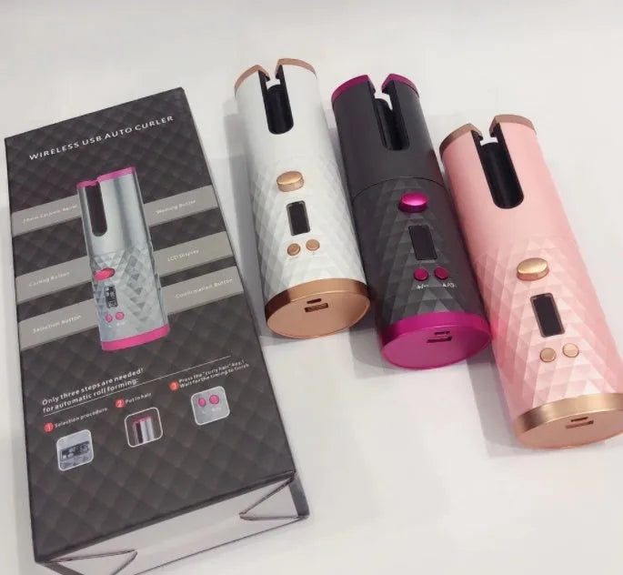 White automatic wireless curling iron with a gold ceramic barrel on a table next to a USB cable.