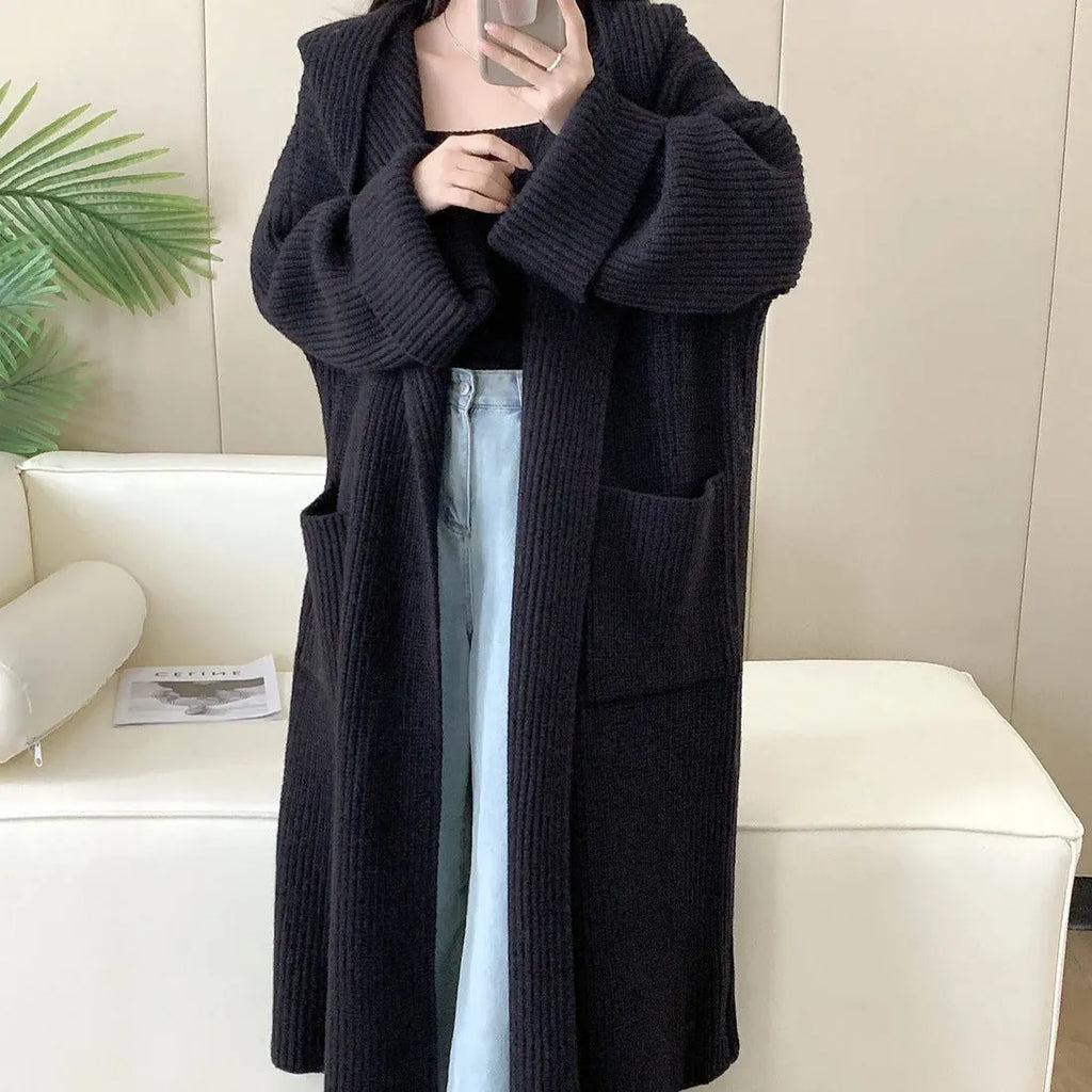 A woman wearing a long, loose, milky white hooded cardigan coat with raglan sleeves.