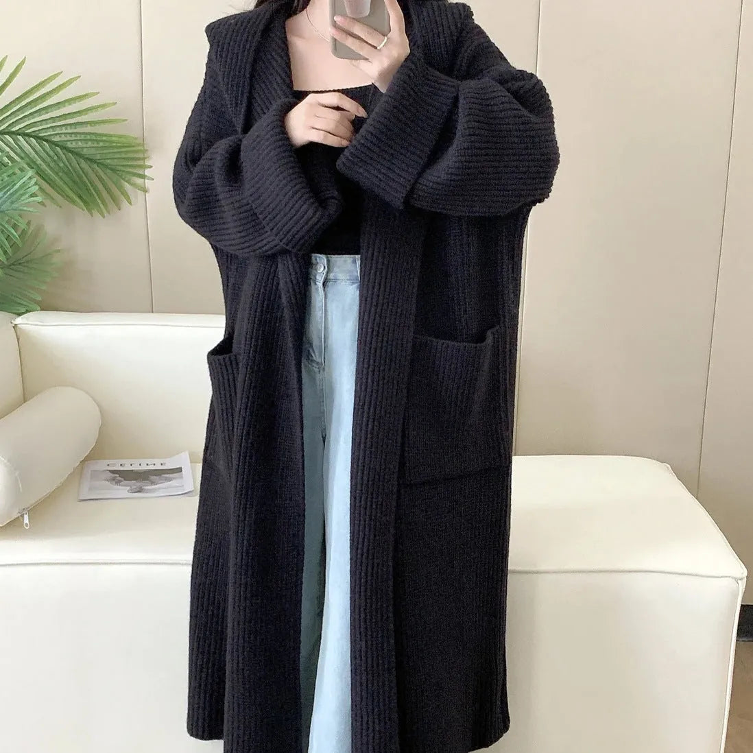 A woman wearing a long, loose, milky white hooded cardigan coat with raglan sleeves.