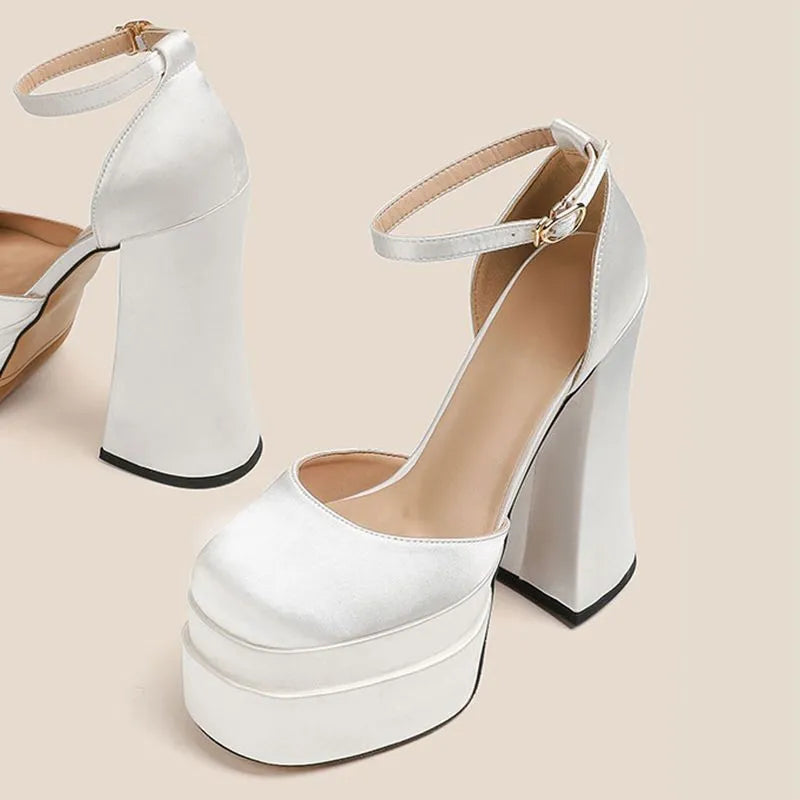 Women's white chunky heel platform pumps with a round toe and ankle strap on a plain background.