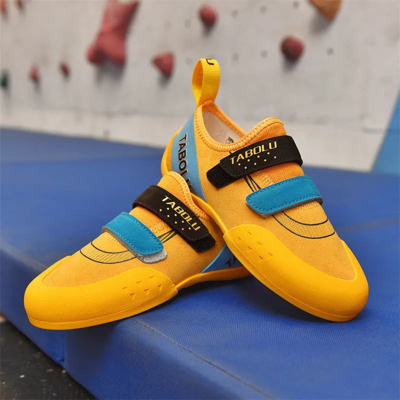 A pair of beginner rock climbing shoes with velcro straps in a black and red colour combination.