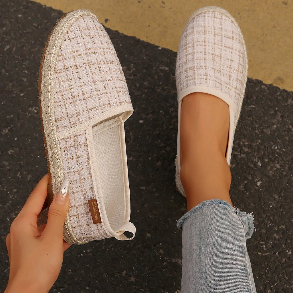 Casual beige canvas fisherman shoes with a textured rope sole on a wooden floor.