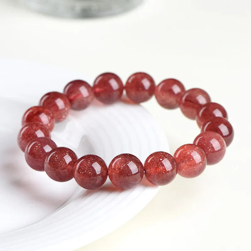 Cherry red strawberry quartz crystal bracelet with geometric beads on a wrist.