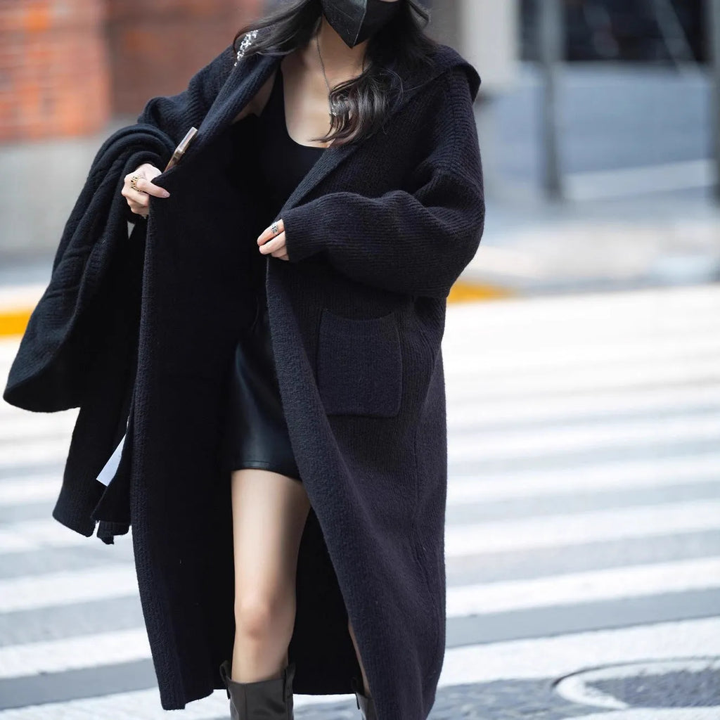 Long grey knitted women's cardigan with hood and trench coat design, shown open as a front-fastening garment.