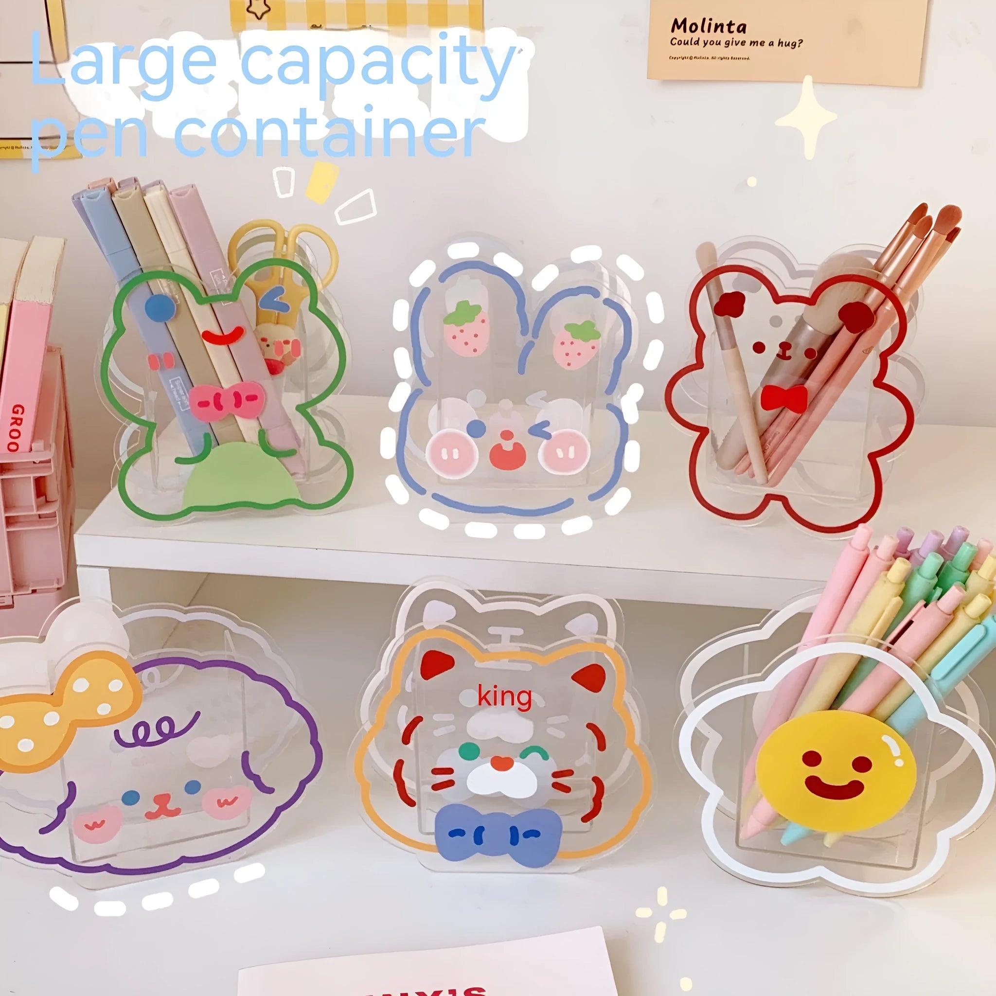 Clear square acrylic storage box with a colourful printed lid featuring a cute design, shown holding pens and stationery.