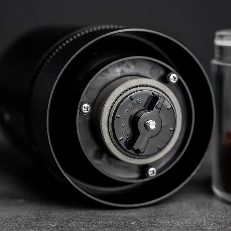 Black and white portable USB-C electric coffee grinder with transparent chamber on a kitchen counter