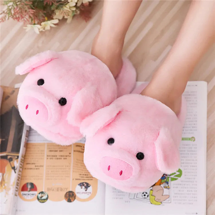Pink pig-shaped plush house slippers with a short pile exterior, shown on a plain background.