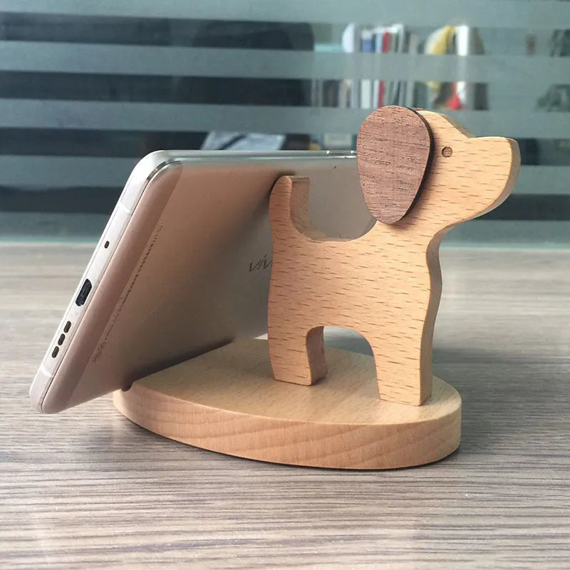 Sculpted beech wood lazy bracket phone holder with custom engraved text on a wooden desk.