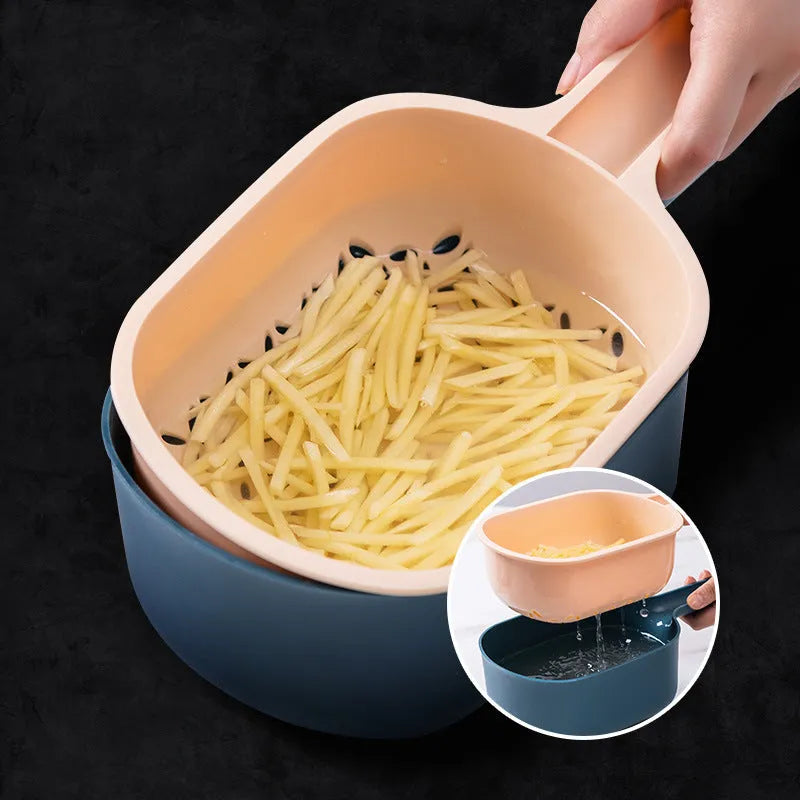 Dark blue vegetable cutter with four stainless steel blades, a hand guard, and a drain basket on a kitchen counter.