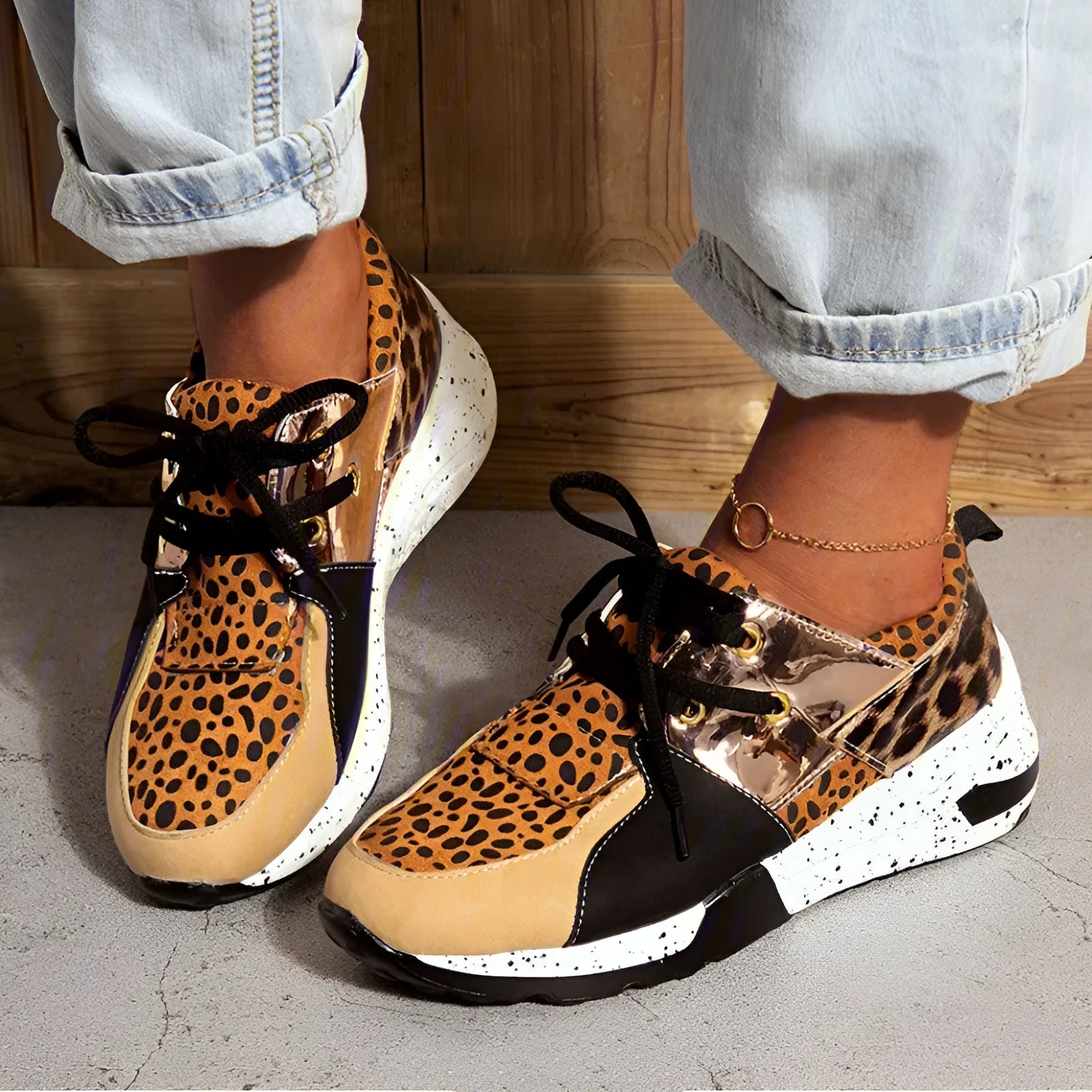 Women's black suede wedge sneakers with a round toe and low-cut design on a wooden floor.