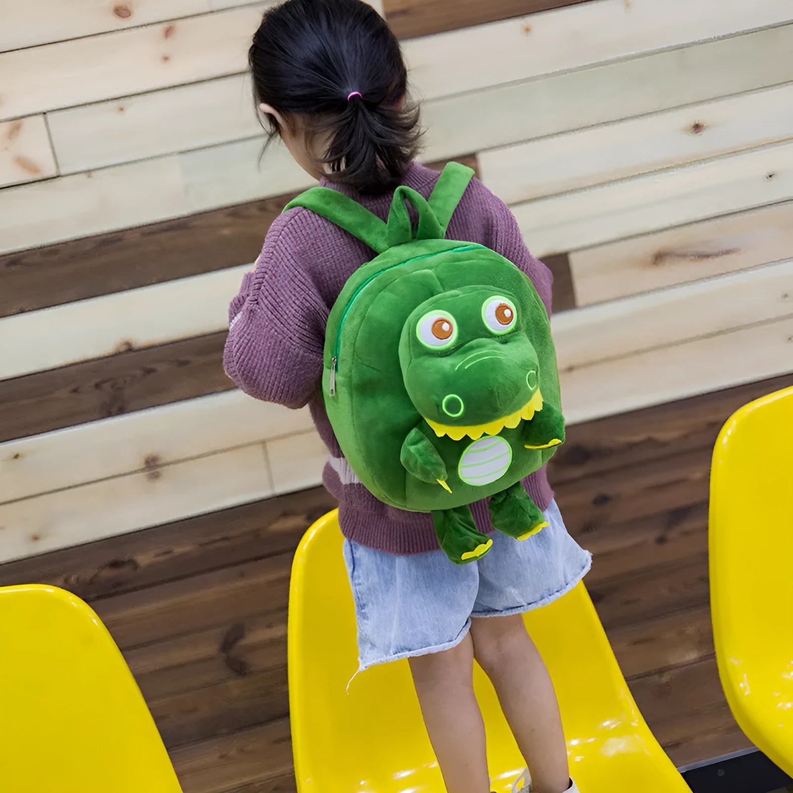 Soft blue plush children's backpack with an embroidered dinosaur character and a soft handle.