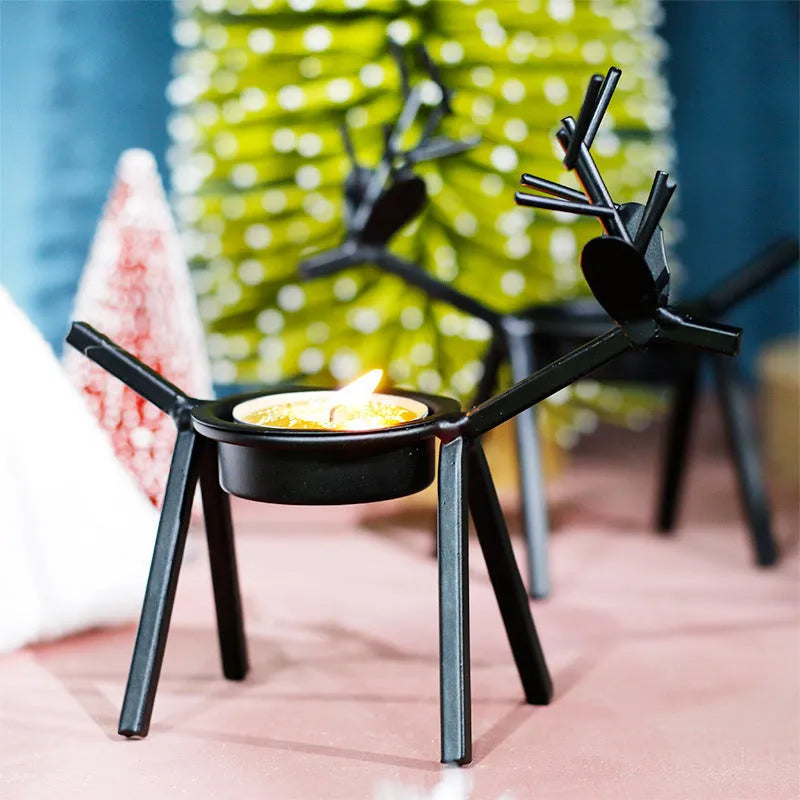 Black iron Christmas candlestick with deer and elk bracket design on a table.