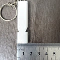 Close-up of a silver aluminium alloy double-hole outdoor survival whistle on a dark background.