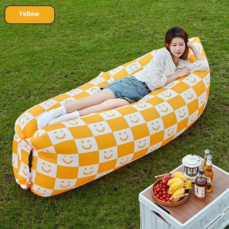 Inflatable lazy sofa in yellow smiling face tip colour, folded for transport with one-minute inflation valve visible