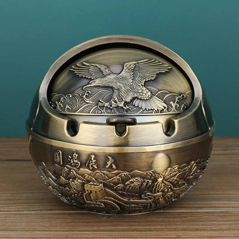 Bronze and red copper alloy decorative ashtray with smoke-extinguishing slot on a table.