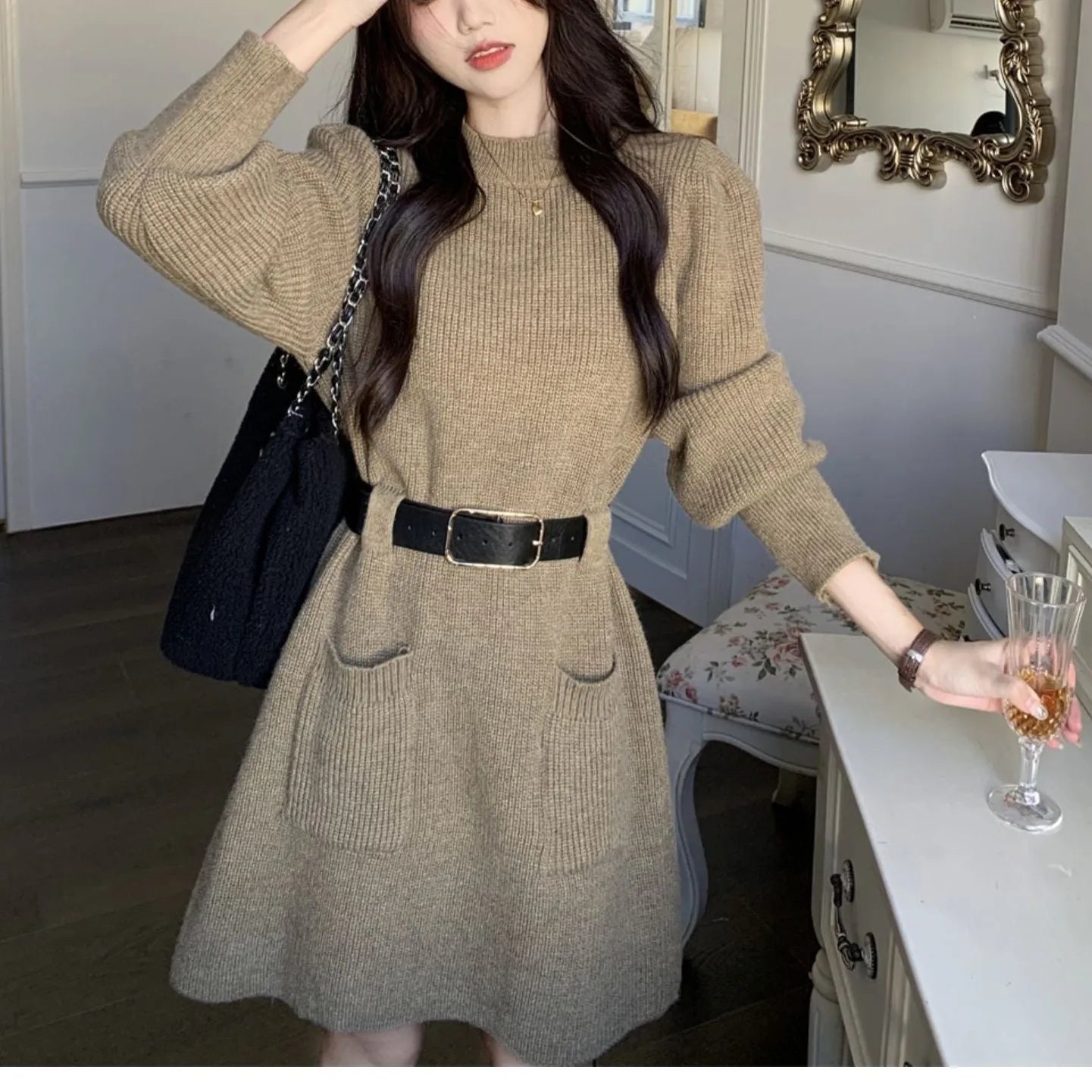 Women's beige long sleeve loose knit dress with a black belt on a hanger.
