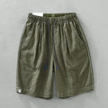 Men's loose fit linen shorts in green on a hanger, showing straight leg and drawstring waist.