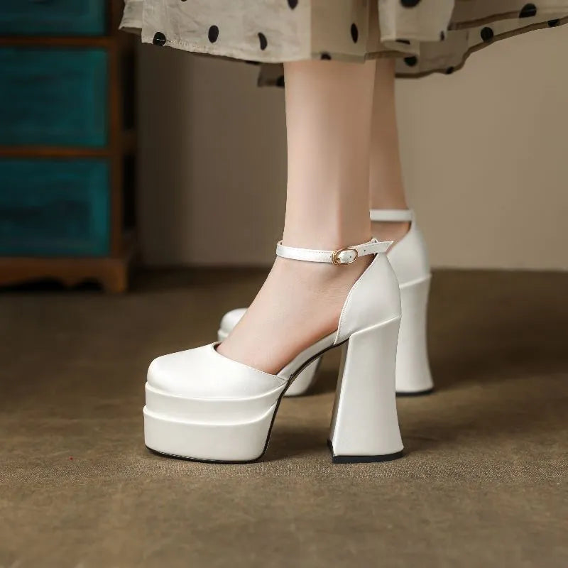 Women's white chunky heel platform pumps with a round toe and ankle strap on a plain background.