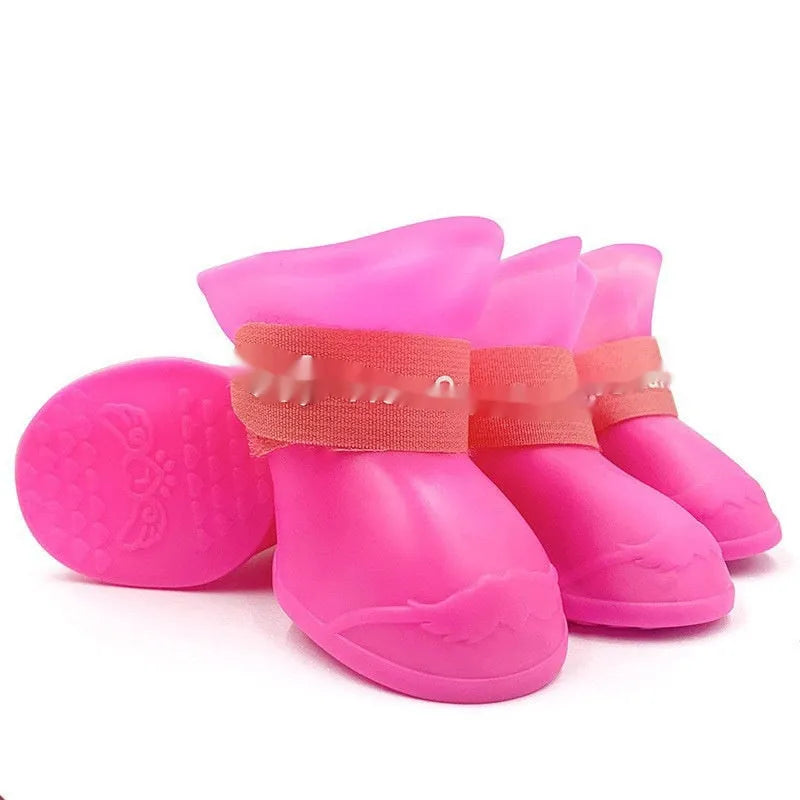 Set of four colourful rubber dog rain shoes with anti-slip soles on a wet surface.