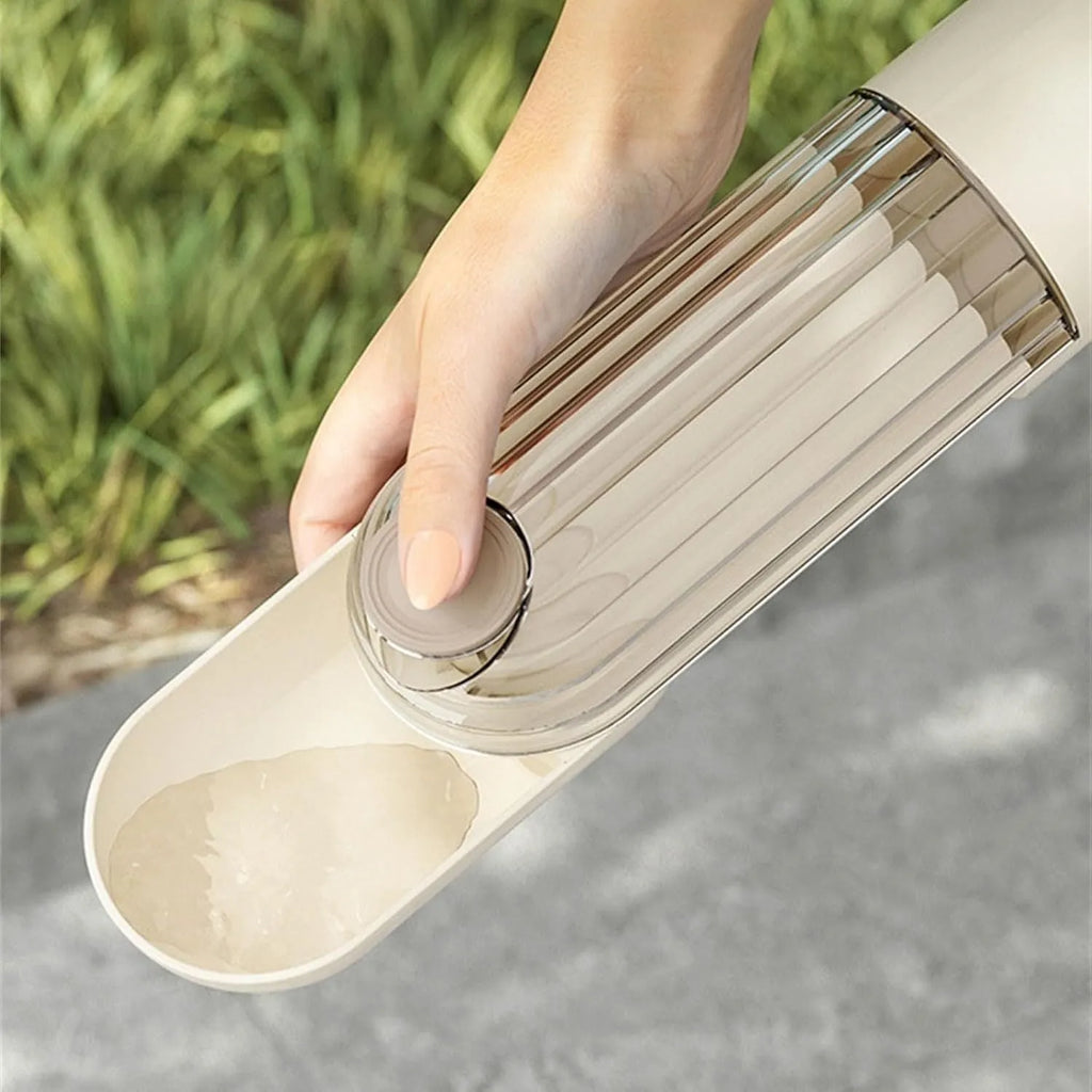 Beige and green foldable dog water bottle with food dispenser for outdoor use.