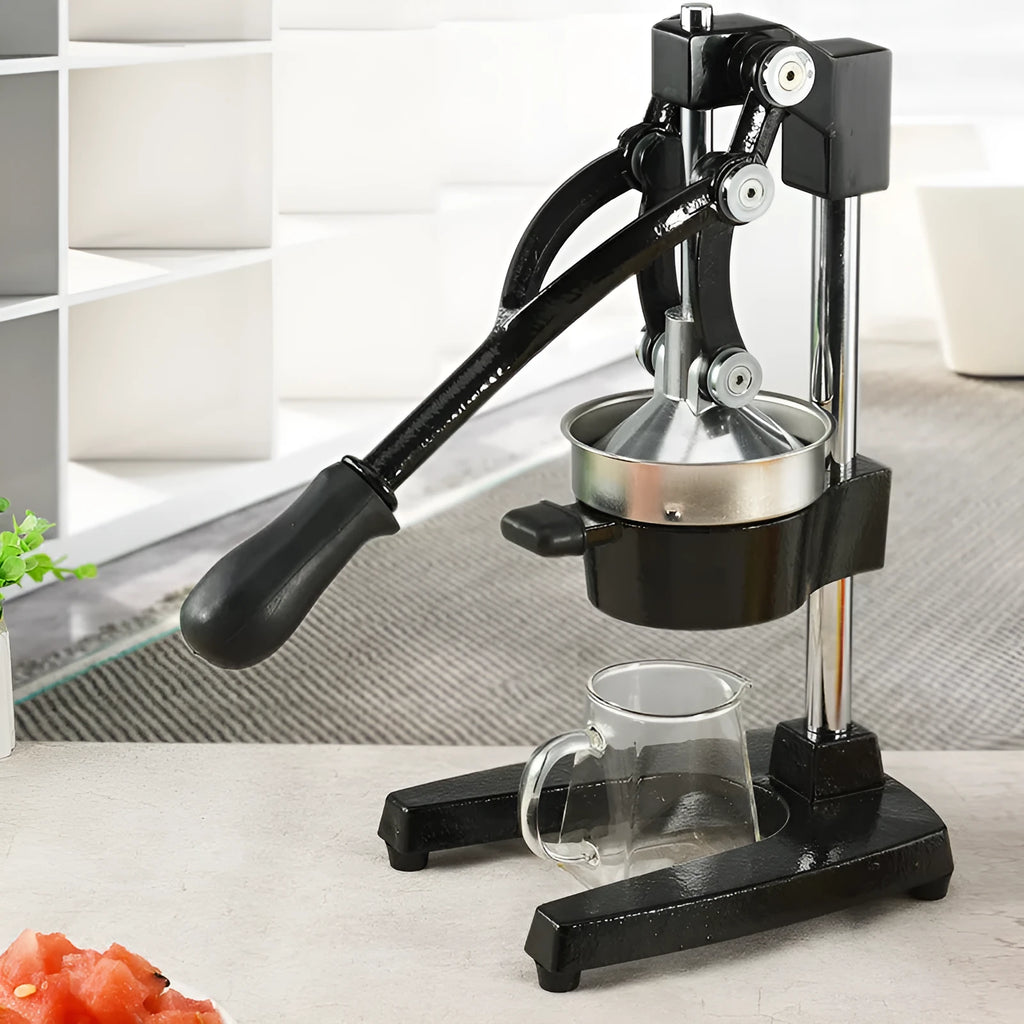 Black and white manual cast iron juice press with stainless steel funnel, standing 40cm high.