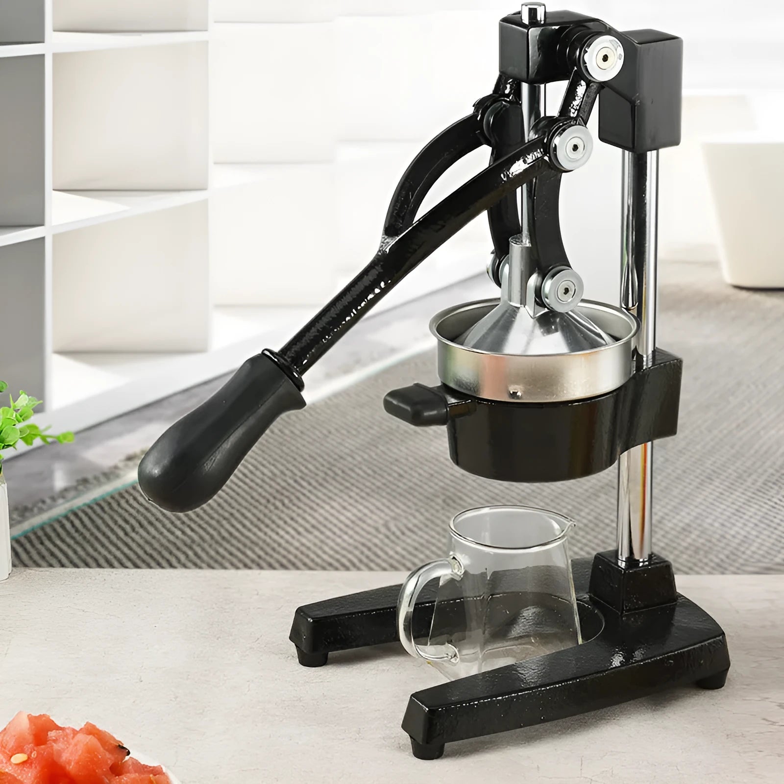 Black and white manual cast iron juice press with stainless steel funnel, standing 40cm high.