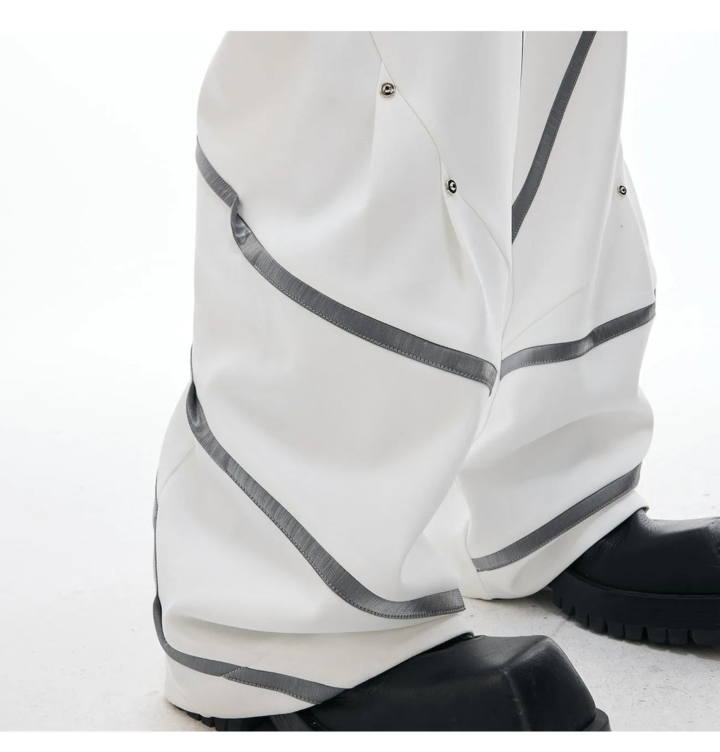 Men's black polyester trousers with metal rivet stripe and front pleats on a white background.
