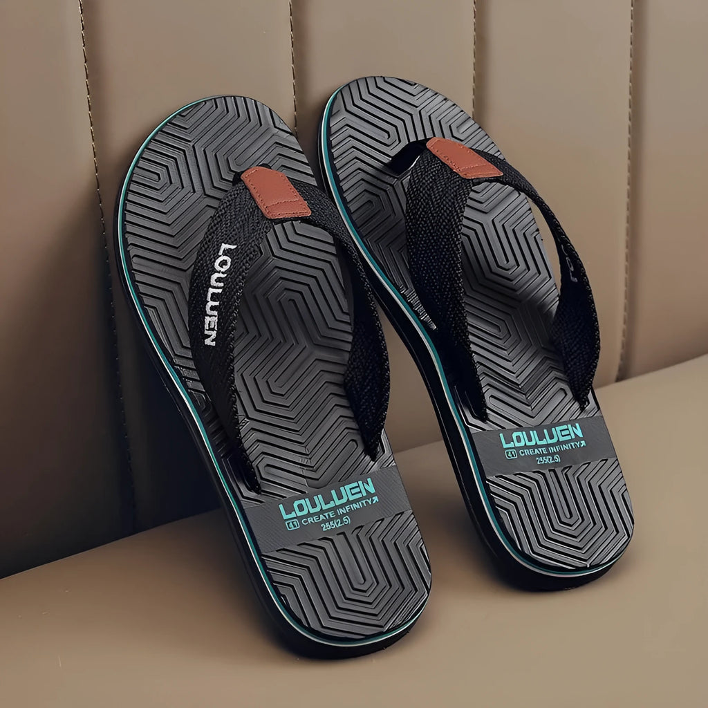 Men's black flip flops with textured non-slip sole on a beach background.