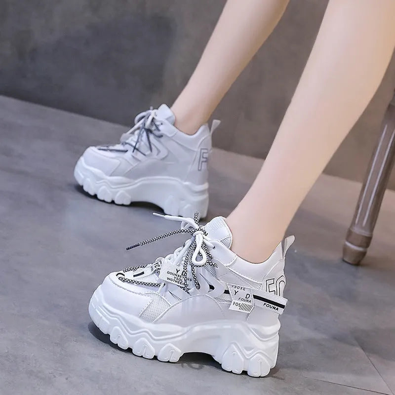 Women's white low-top platform trainers with mesh panels and a cross-strap detail.