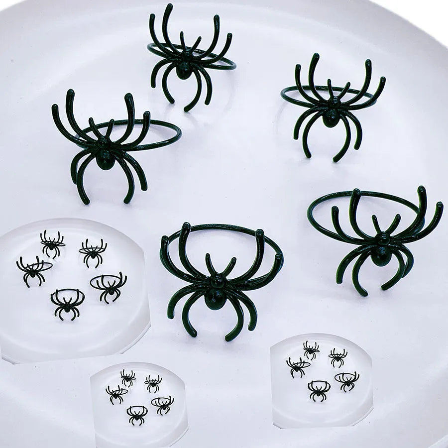 Set of six black alloy Halloween napkin rings with detailed spider design on a table setting.