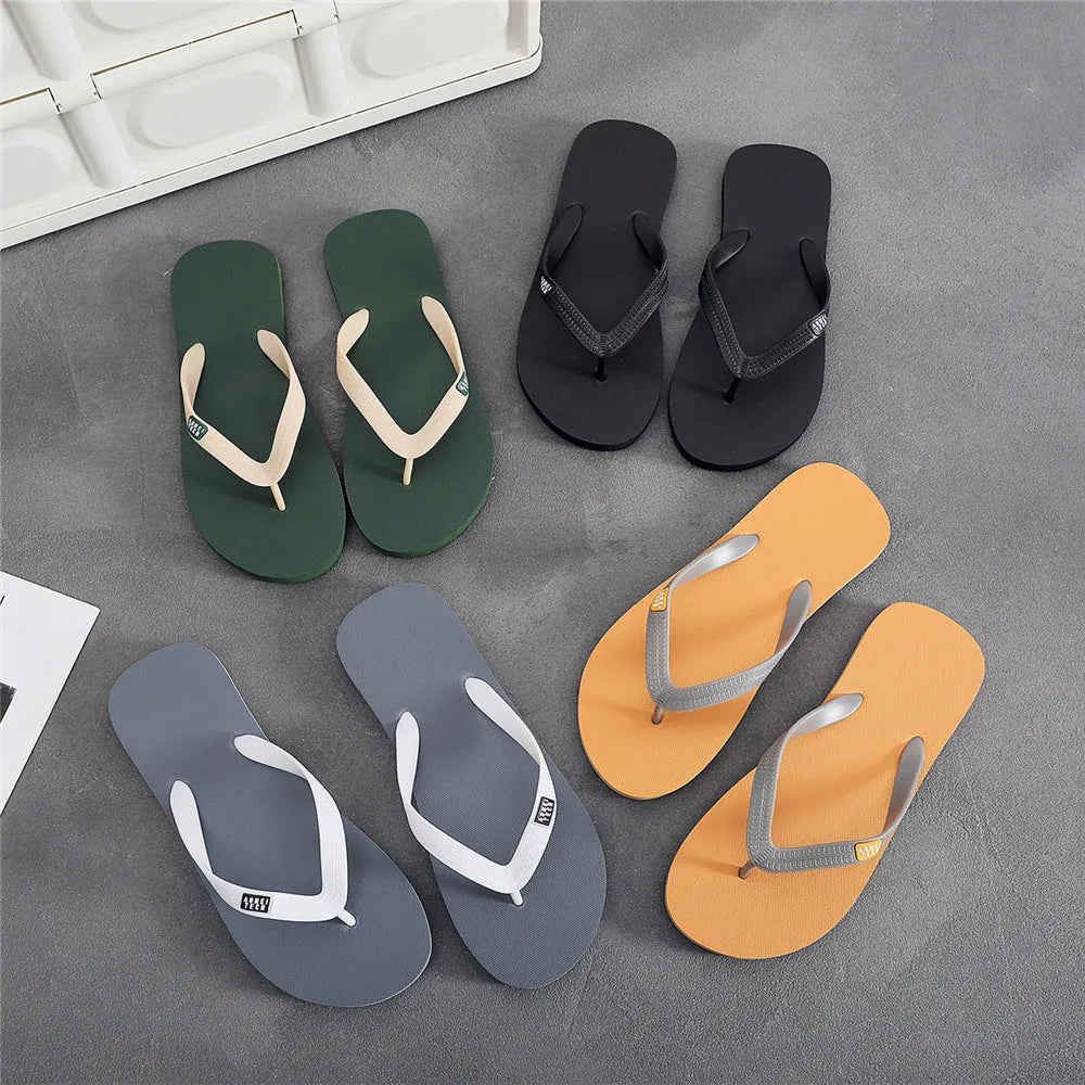 Men's black flip-flops with a textured rubber sole and a lightweight EVA upper on a sandy beach.